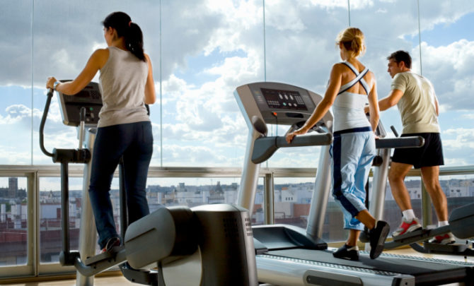 People using exercise equipment in front of a window