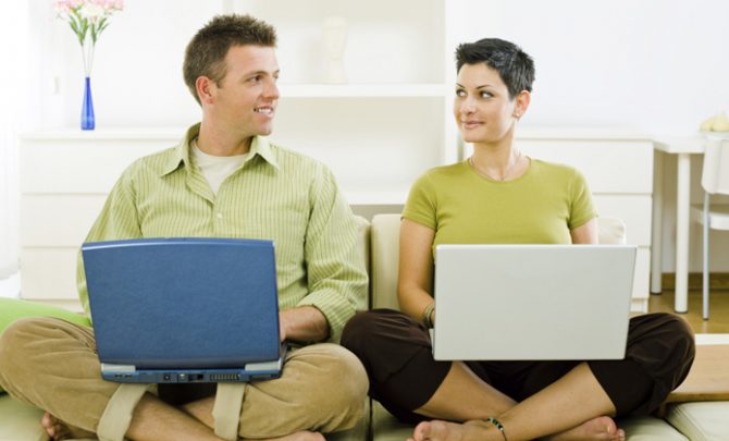 Young couple sitting on a sofa cross-legged in the living room, using laptops, looking at each other. [url=my_lightbox_contents.php?lightboxID=1507925][img]http://www.nitorphoto.com/istocklightbox/peopleathome.jpg[/img][/url]