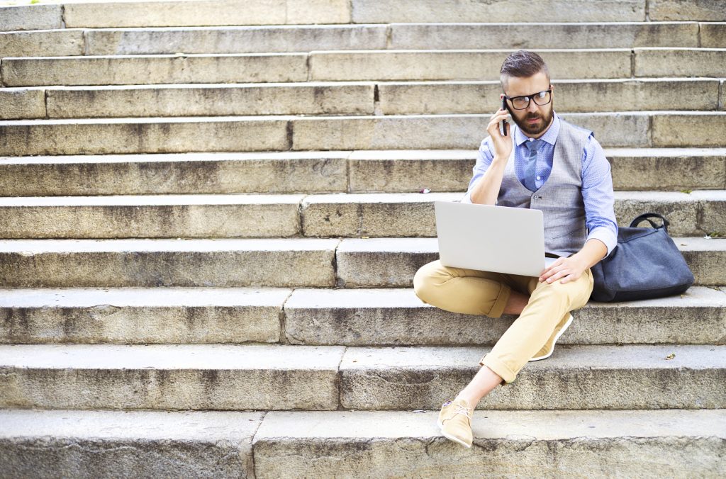 Hipster businessman with phone and laptop